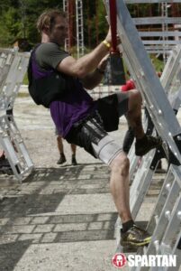 man climbing white scaffolding for a spartan race