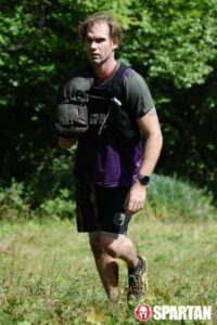 man moves through field with sandbag over shoulder